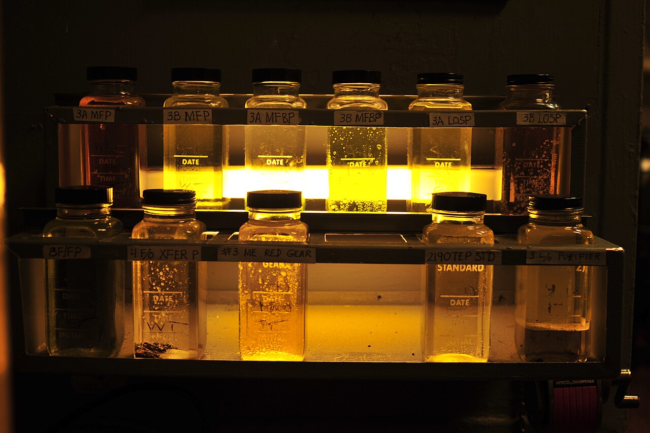 Labeled lubricant sample bottles arranged on a rack aboard USS Midway
